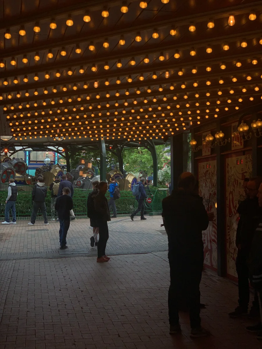 People walking beneath rows of warm lights in a Tivoli arcade