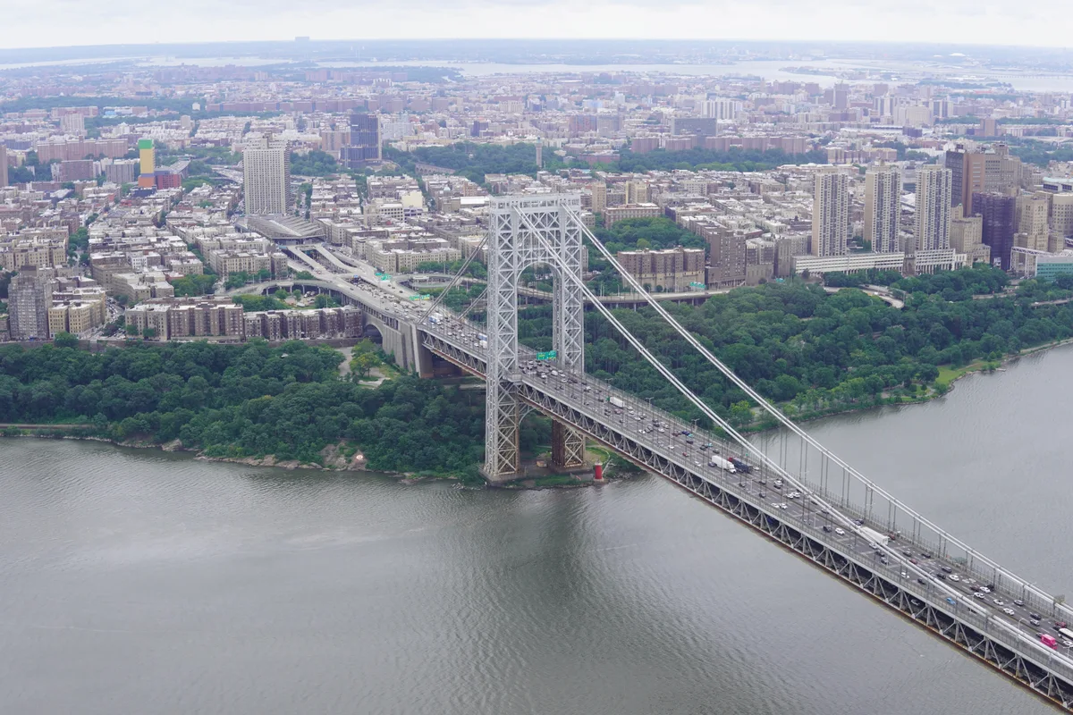 An aerial view of the George Washington Bridge crossing the river beside wooded banks